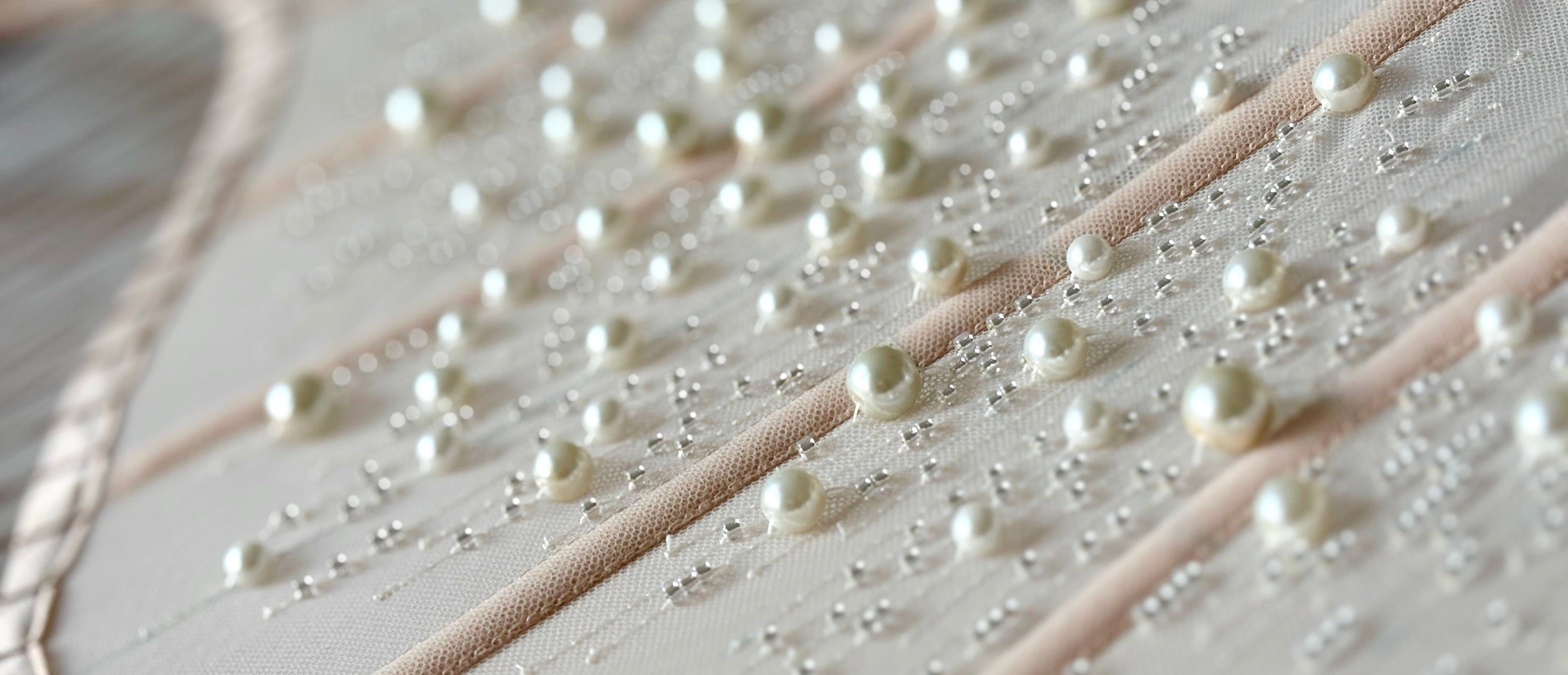 Close-up of a fabric with pearl-like beads on a white background
