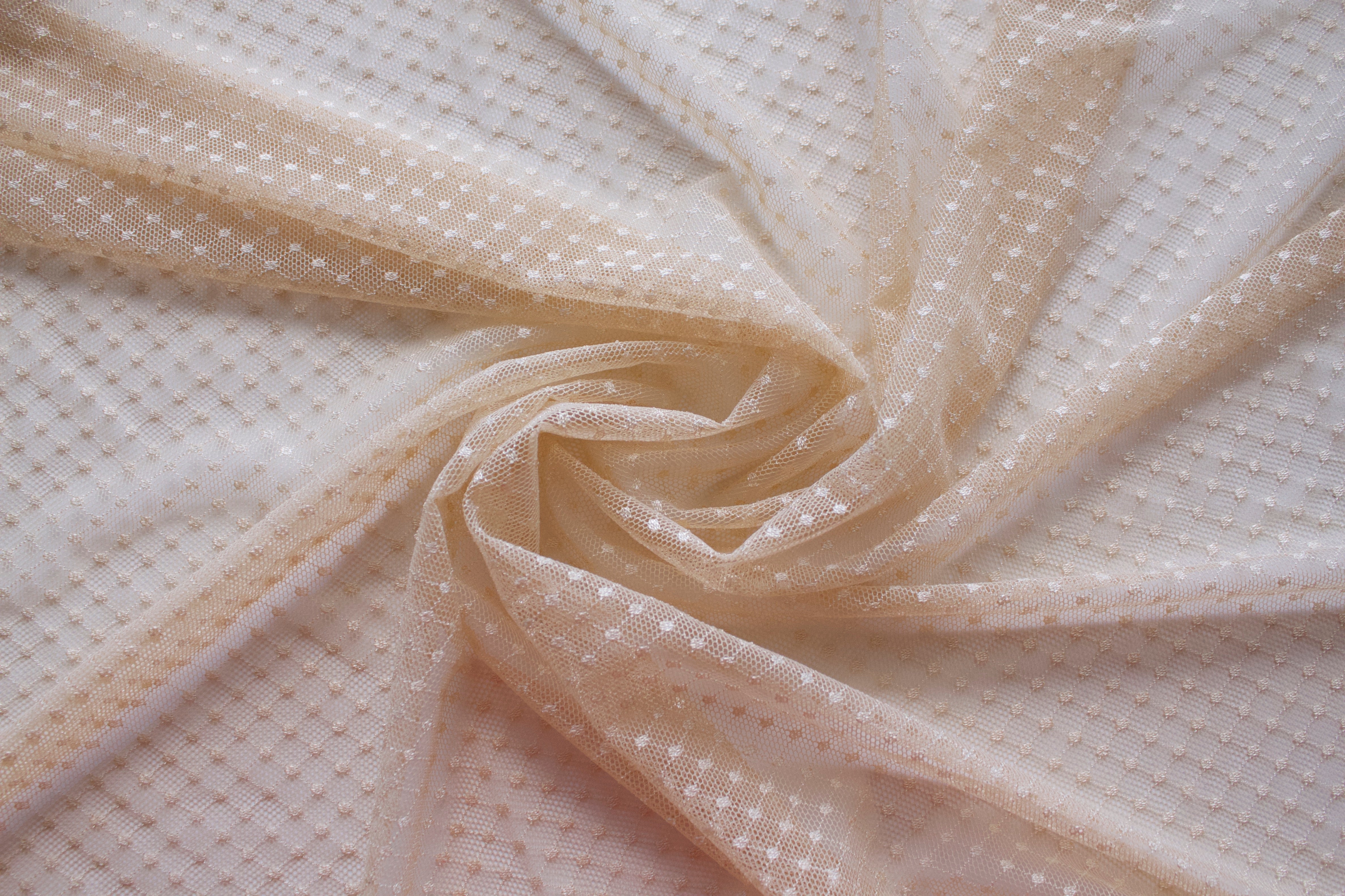 Close up of a dotted lace fabric in the color beige from Rubies Custom Bras. Book a online fitting appointment to have a custom bra made today. A custom bra is worth the price because it is custom made to fit and made to last years.