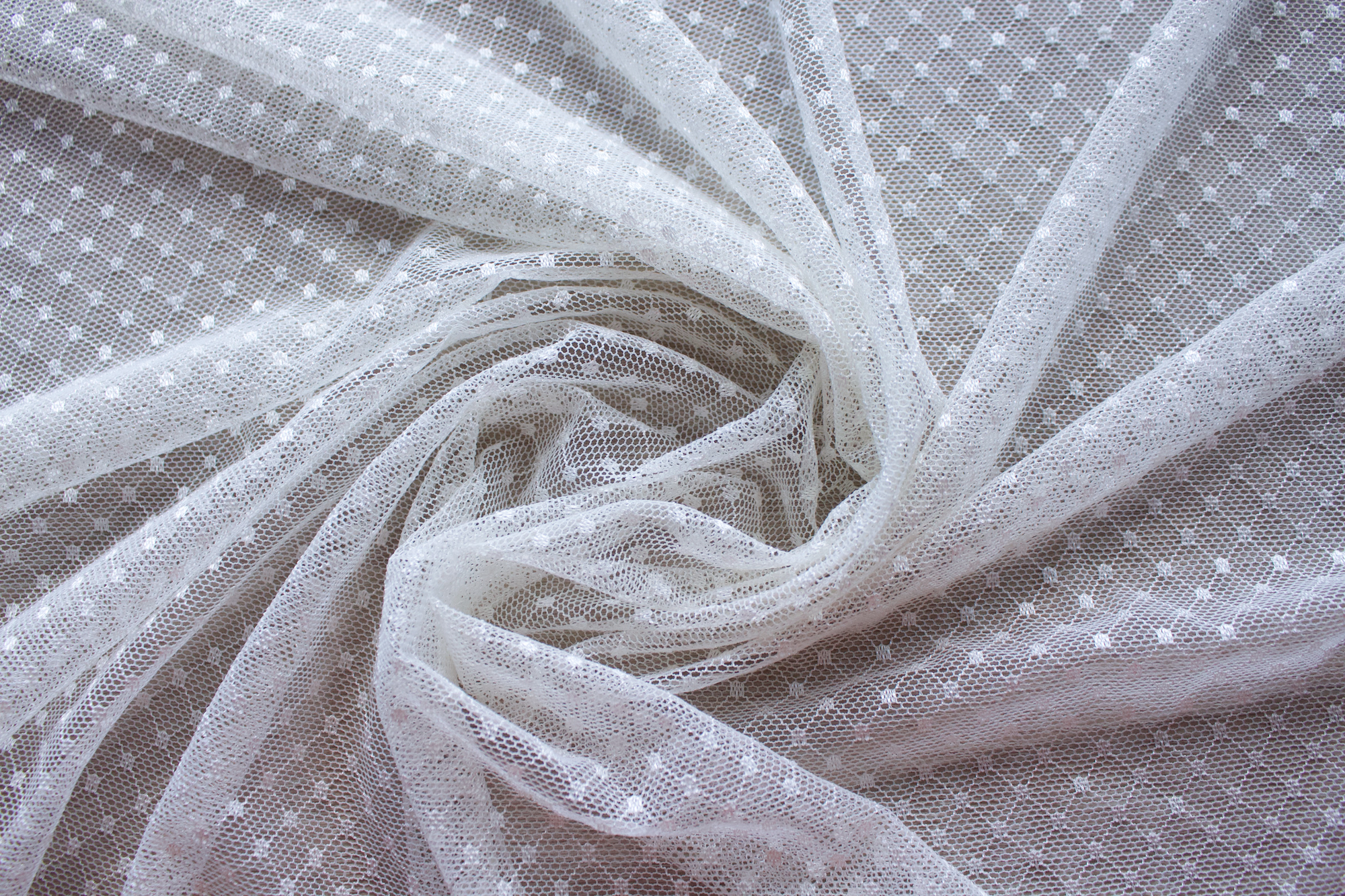 Close up of a dotted lace fabric in the color white from Rubies Custom Bras. Book a online fitting appointment to have a custom bra made today. A custom bra is worth the price because it is custom made to fit and made to last years.