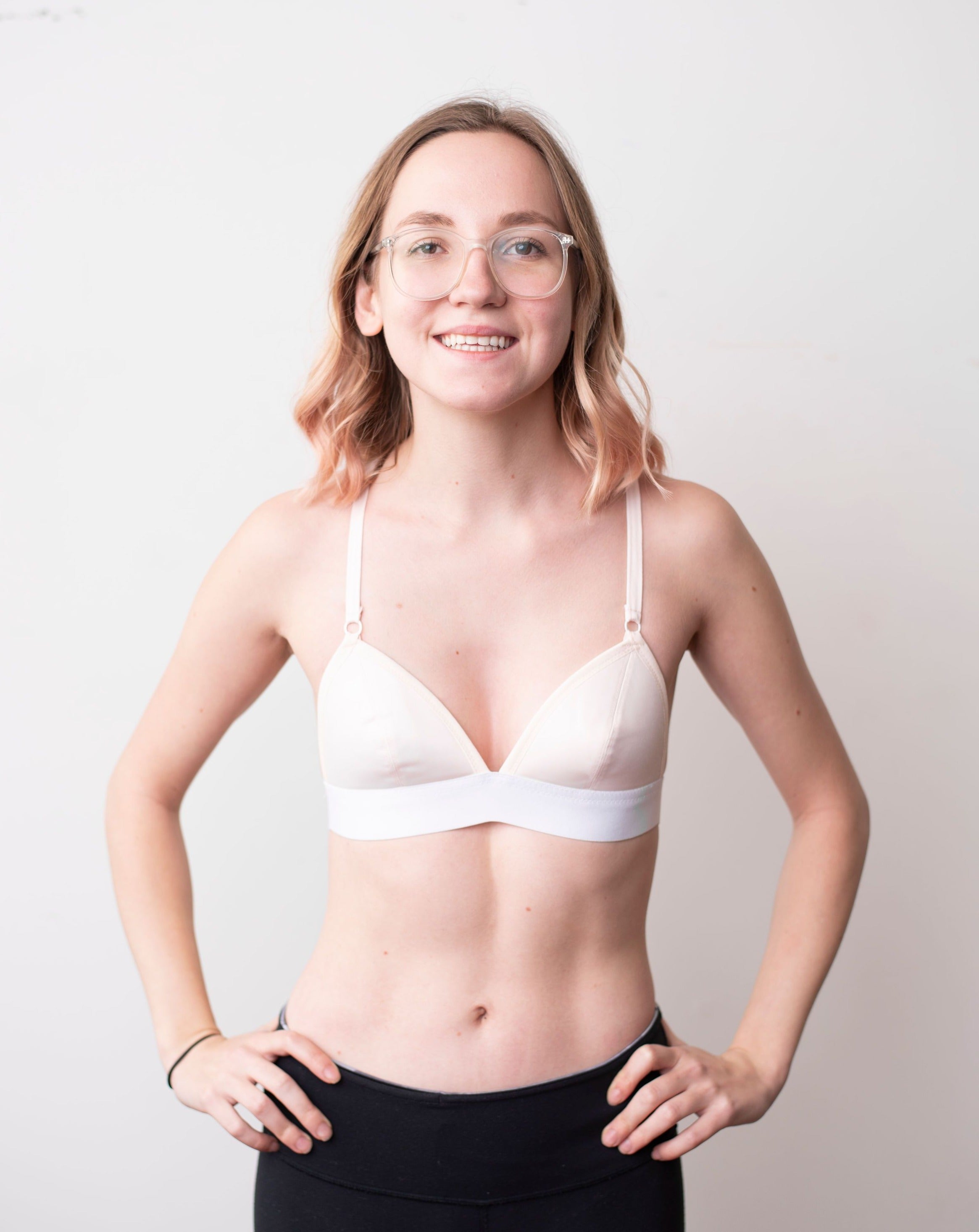 Haley from Rubies Bras, a female with medium blond hair wearing a peach and white wirefree bra from our petites collection. Half body shot on white back drop.