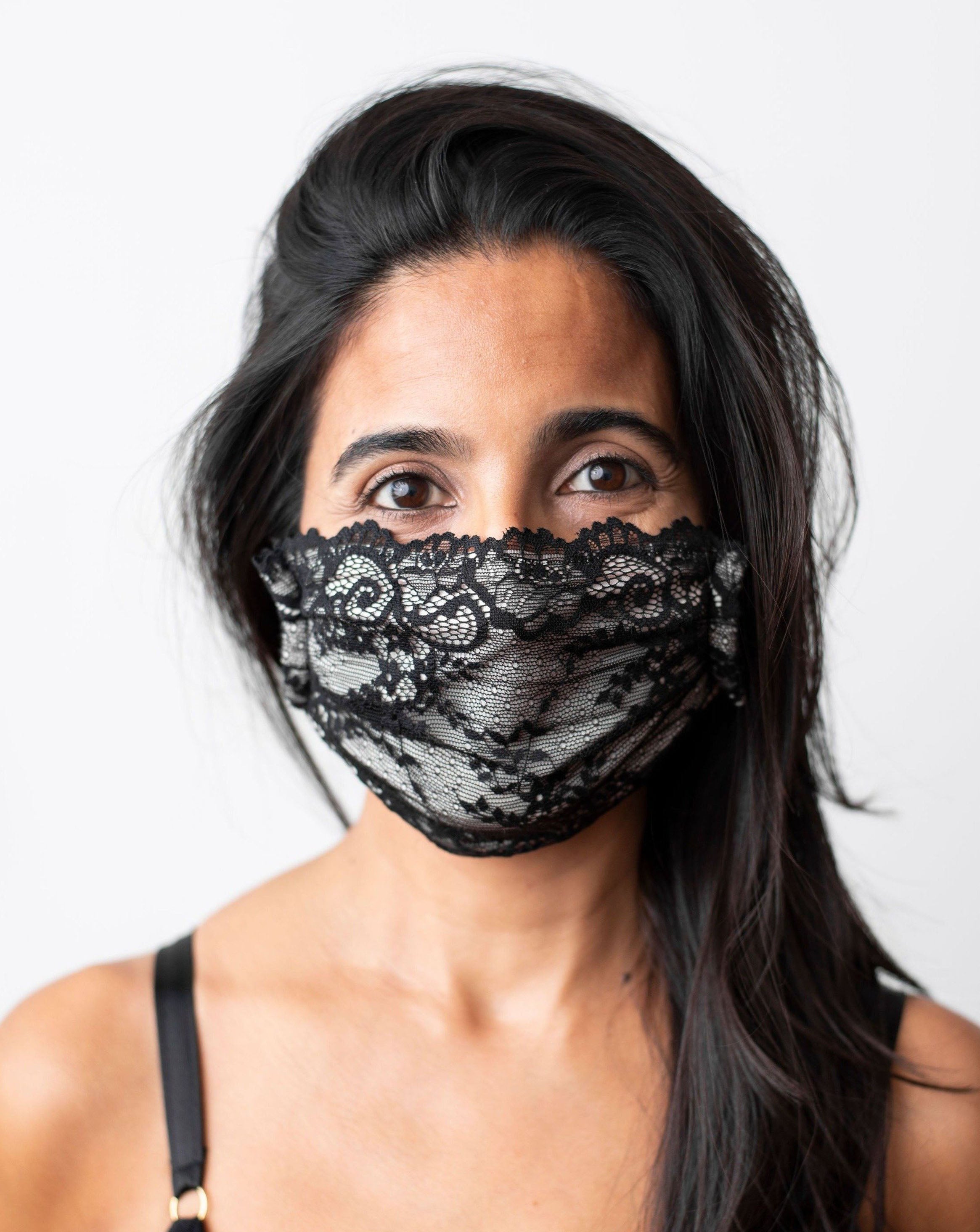 Ruhee, female with long black hair, wearing a black lace, organic cotton mask. Front shot against a plain white background.
