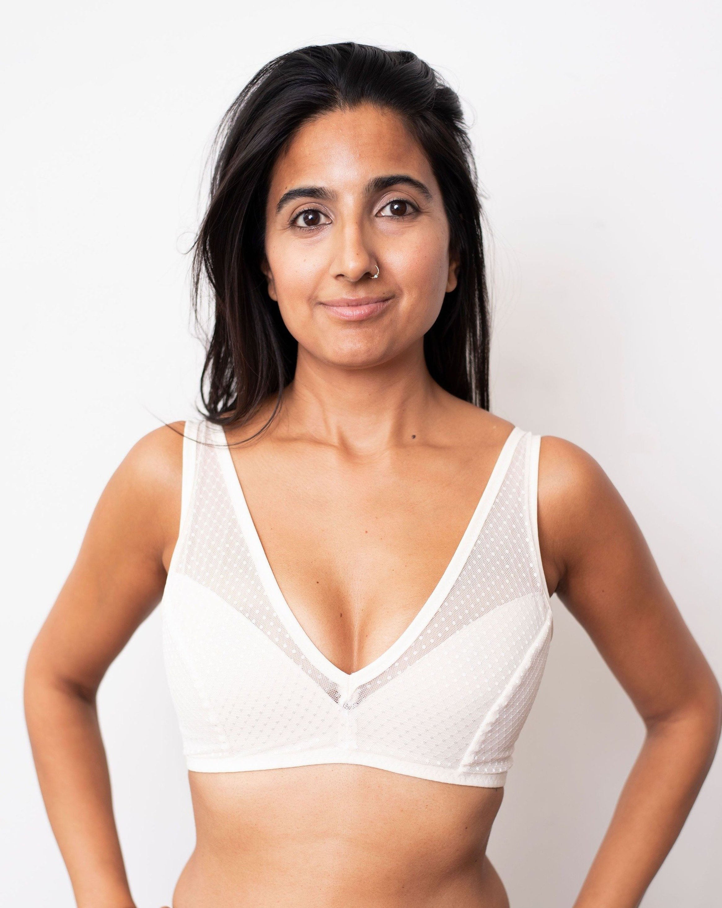 Ruhee from Rubies Bras, a female with long black hair is wearing an ivory dotted lace wirefree bra with deep plunge v neckline. Full front facing body shot on white background.