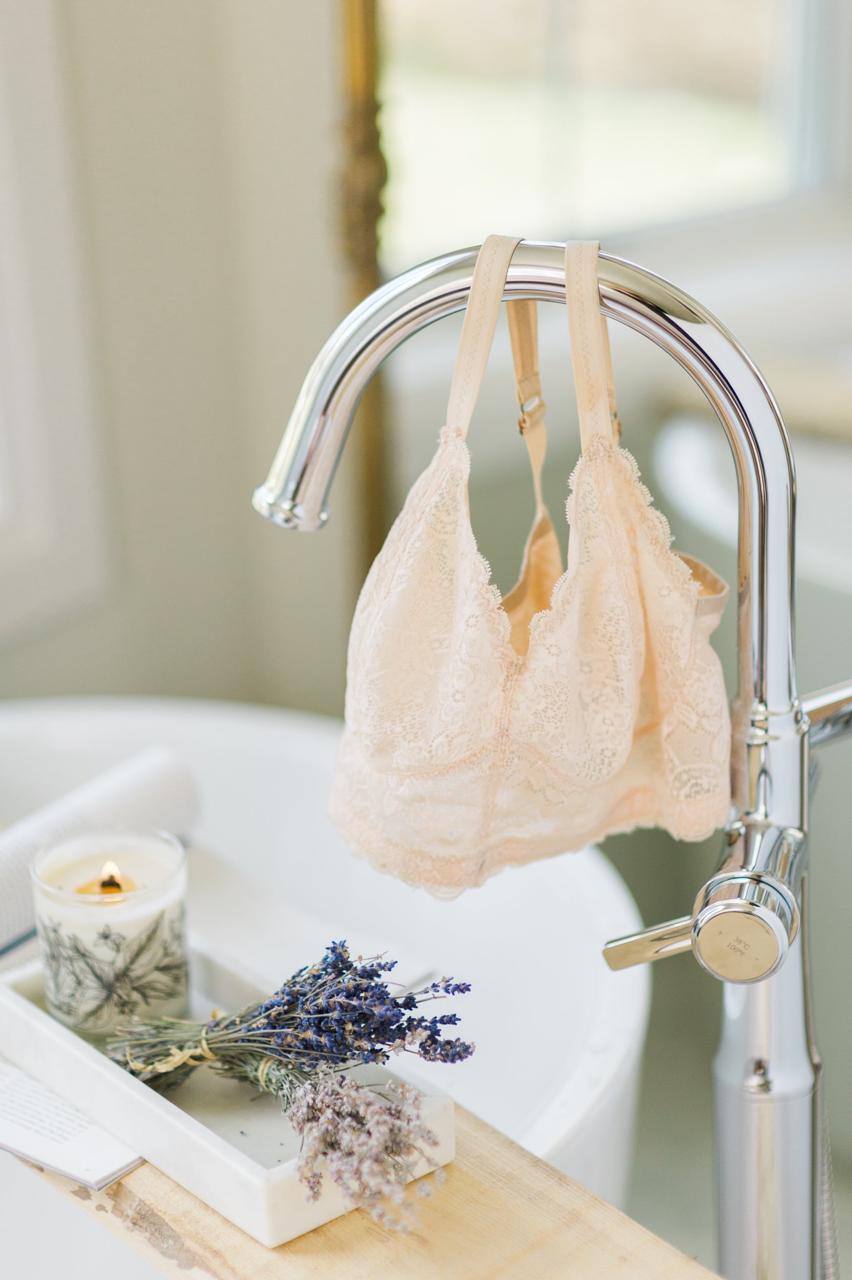 peach lace wireless bra hung on silver spout of bathtub