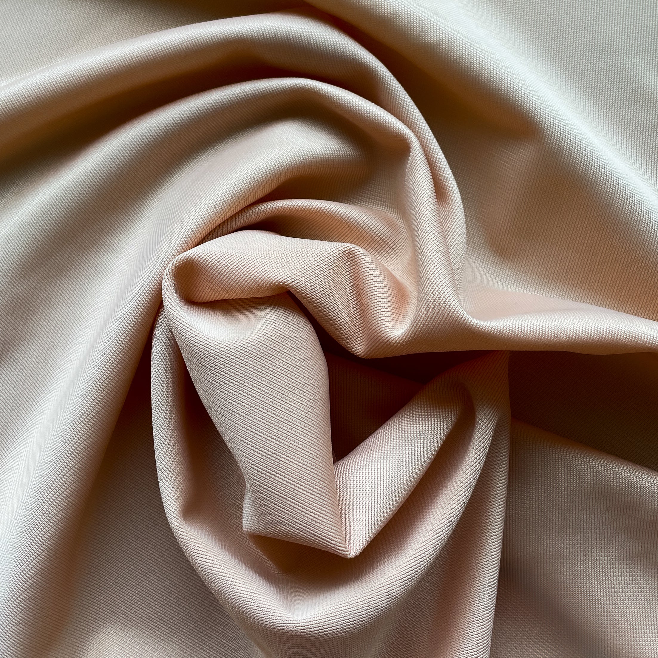 Close up of a soft satin fabric in the color beige from Rubies Custom Bras. We use only the softest bra materials that won't itch or cause allergies. Our fabrics are long lasting and high quality. Book a online fitting appointment to have a custom bra made today. A custom bra is worth the price because it is custom made to fit and made to last years.