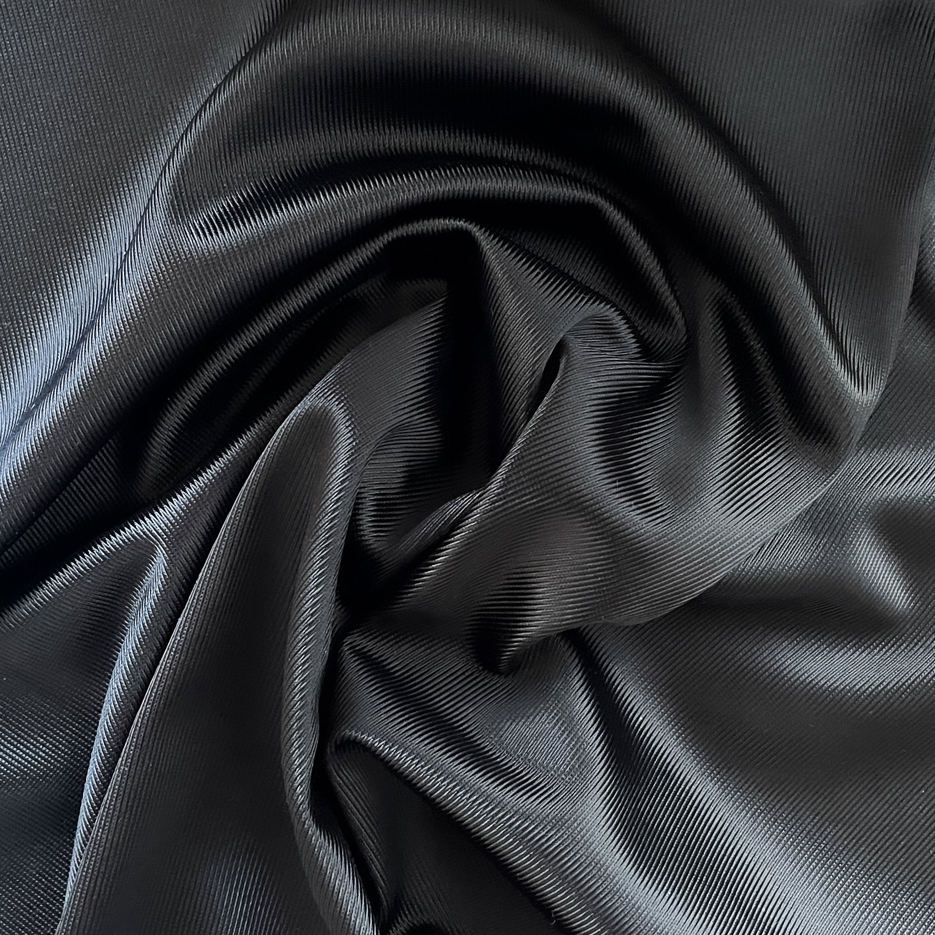 Close up of a soft satin fabric in the color Black from Rubies Custom Bras. We use only the softest bra materials that won't itch or cause allergies. Our fabrics are long lasting and high quality. Book a online fitting appointment to have a custom bra made today. A custom bra is worth the price because it is custom made to fit and made to last years.