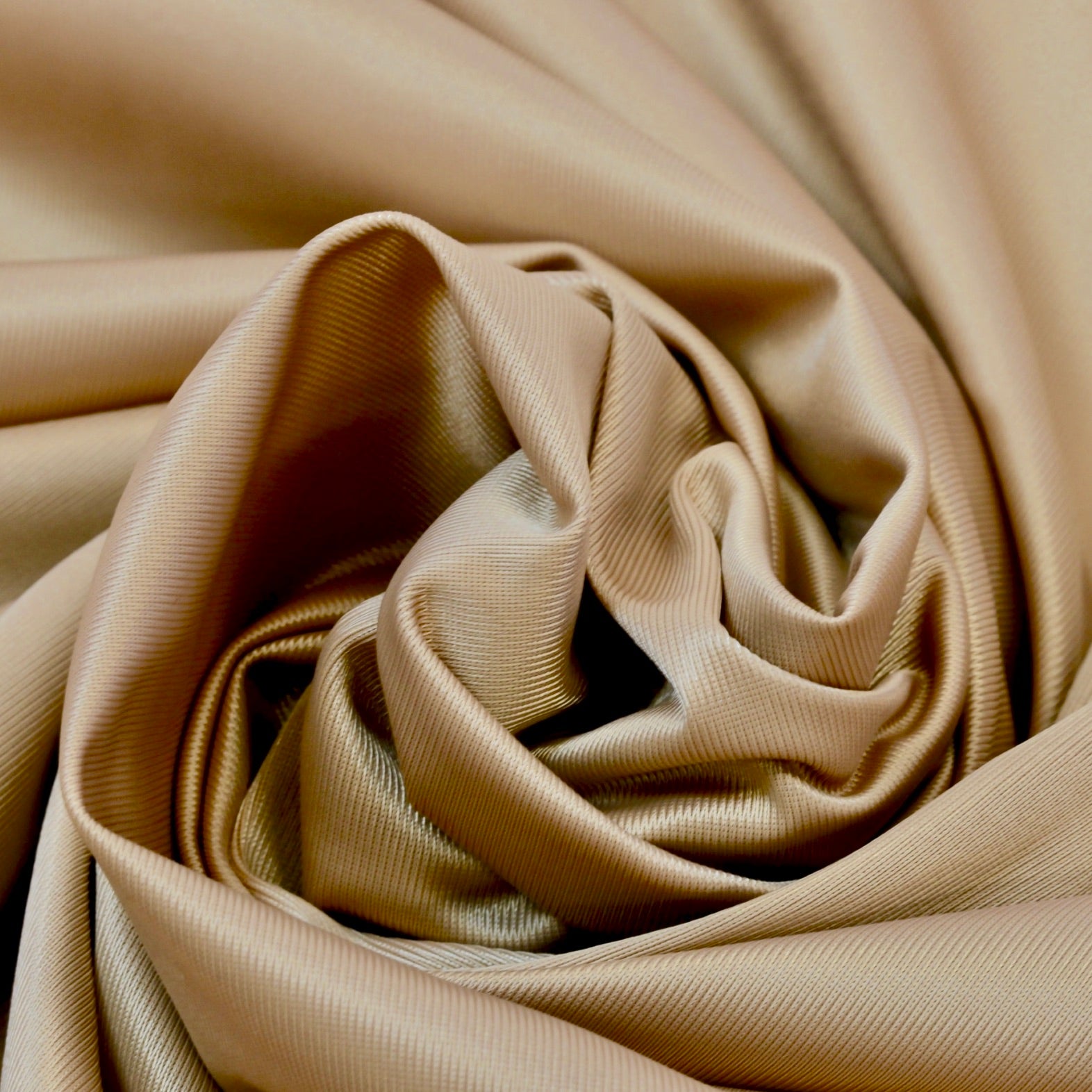 Close up of a soft satin fabric in the color copper from Rubies Custom Bras. We use only the softest bra materials that won't itch or cause allergies. Our fabrics are long lasting and high quality. Book a online fitting appointment to have a custom bra made today. A custom bra is worth the price because it is custom made to fit and made to last years.