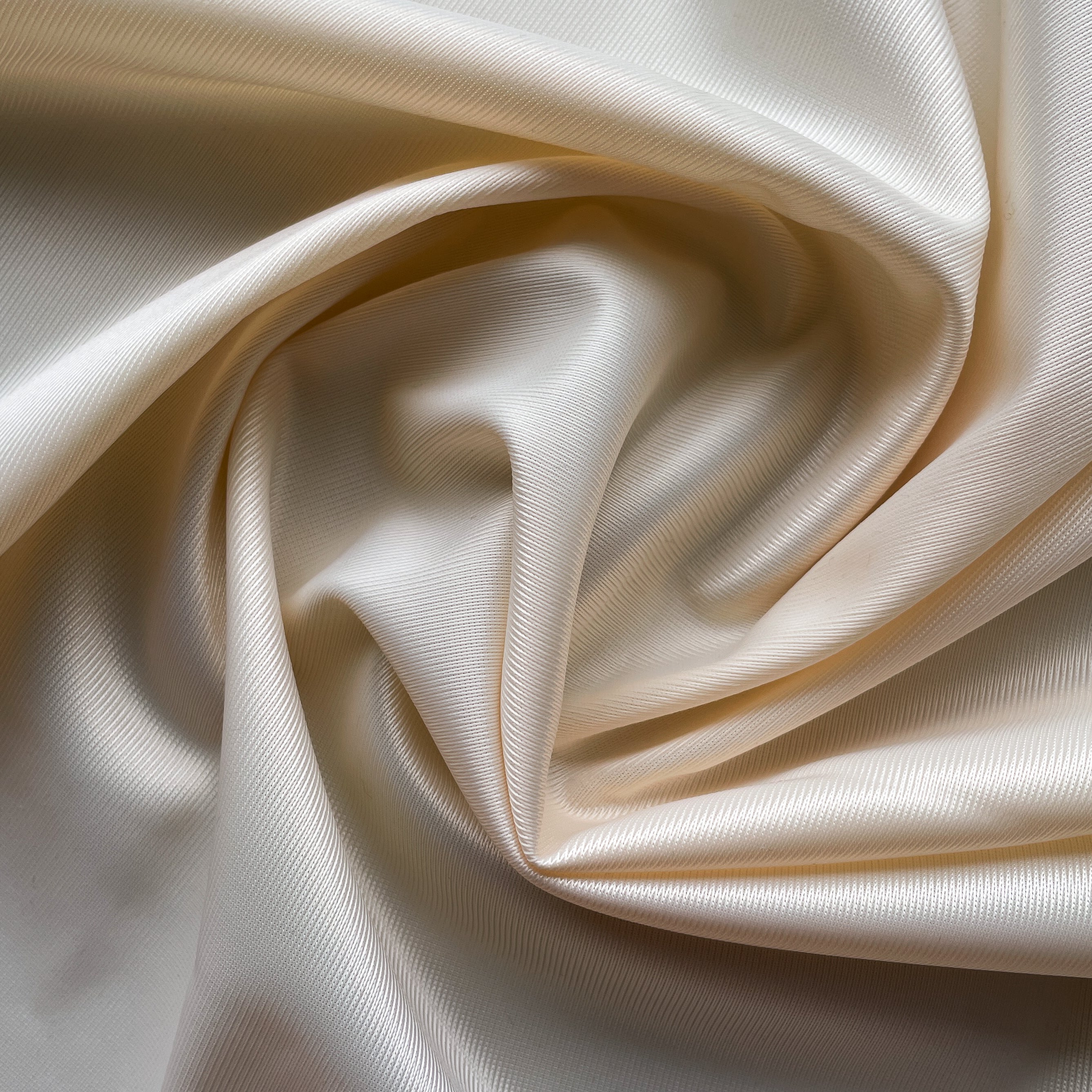 Close up of a soft satin fabric in the color Ivory from Rubies Custom Bras. We use only the softest bra materials that won't itch or cause allergies. Our fabrics are long lasting and high quality. Book a online fitting appointment to have a custom bra made today. A custom bra is worth the price because it is custom made to fit and made to last years.