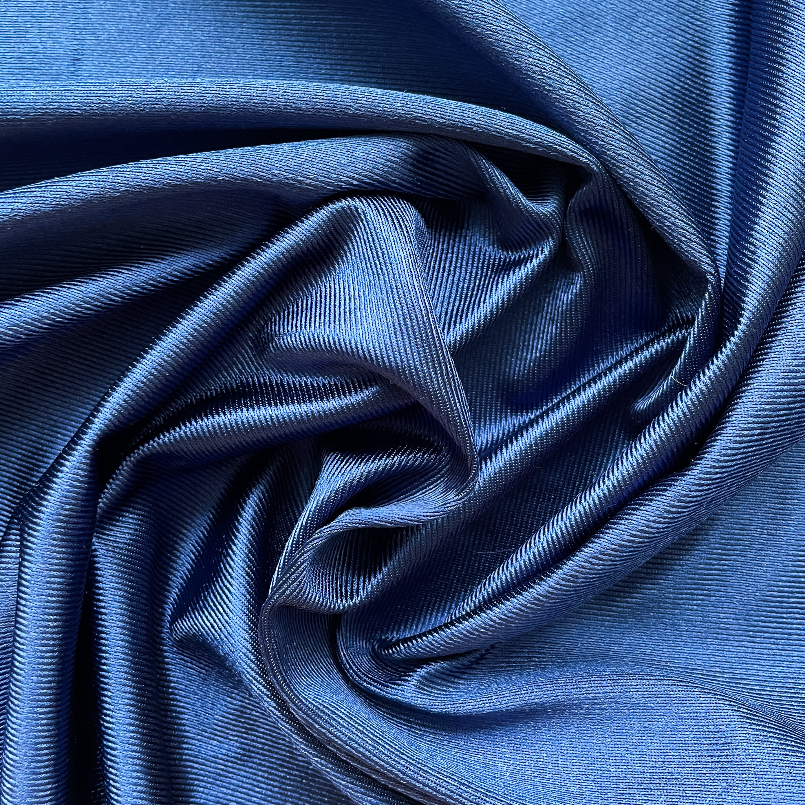 Close up of a soft satin fabric in the color navy from Rubies Custom Bras. We use only the softest bra materials that won't itch or cause allergies. Our fabrics are long lasting and high quality. Book a online fitting appointment to have a custom bra made today. A custom bra is worth the price because it is custom made to fit and made to last years.