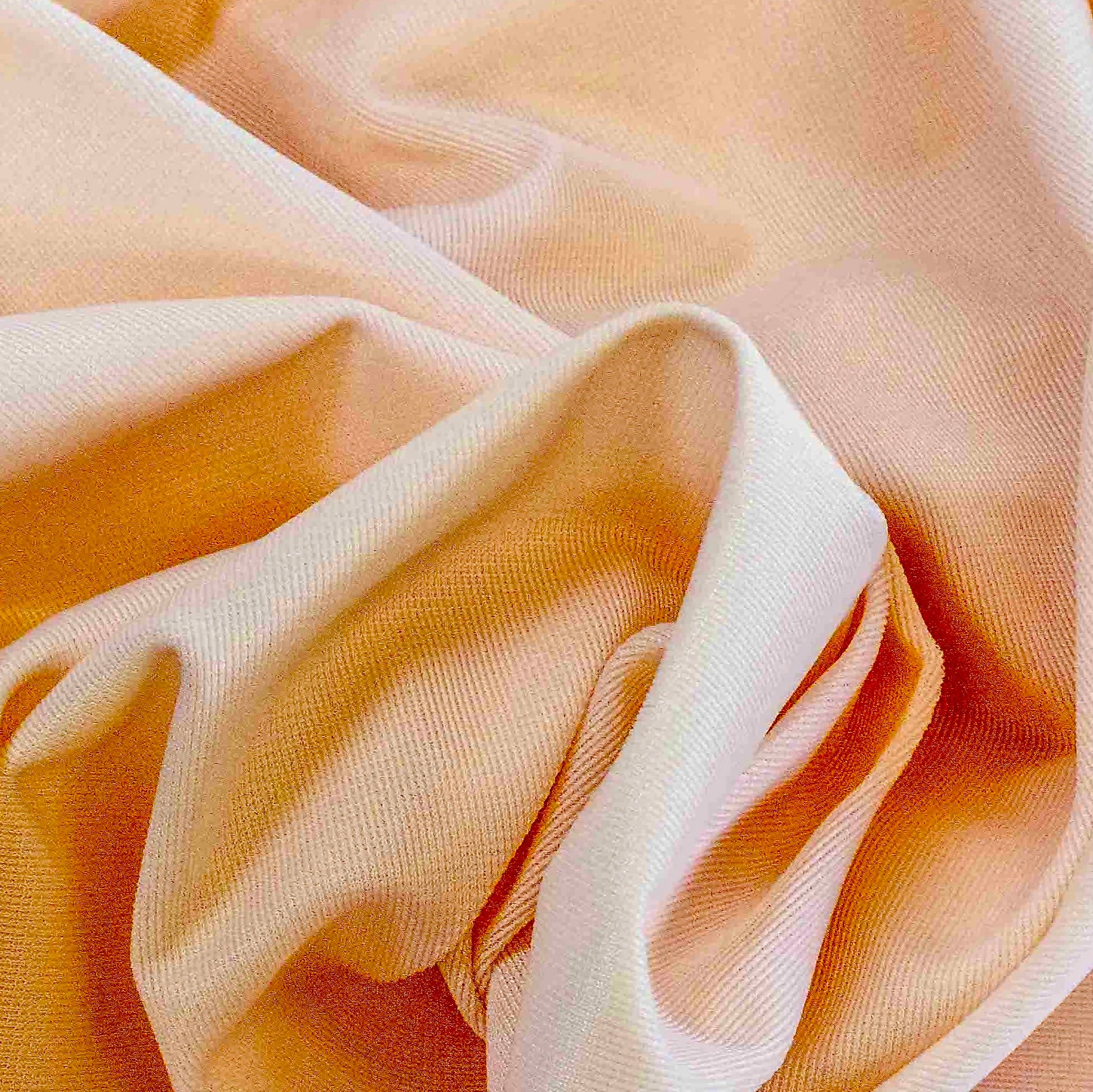 Close up of a soft satin fabric in the color peach from Rubies Custom Bras. We use only the softest bra materials that won't itch or cause allergies. Our fabrics are long lasting and high quality. Book a online fitting appointment to have a custom bra made today. A custom bra is worth the price because it is custom made to fit and made to last years.