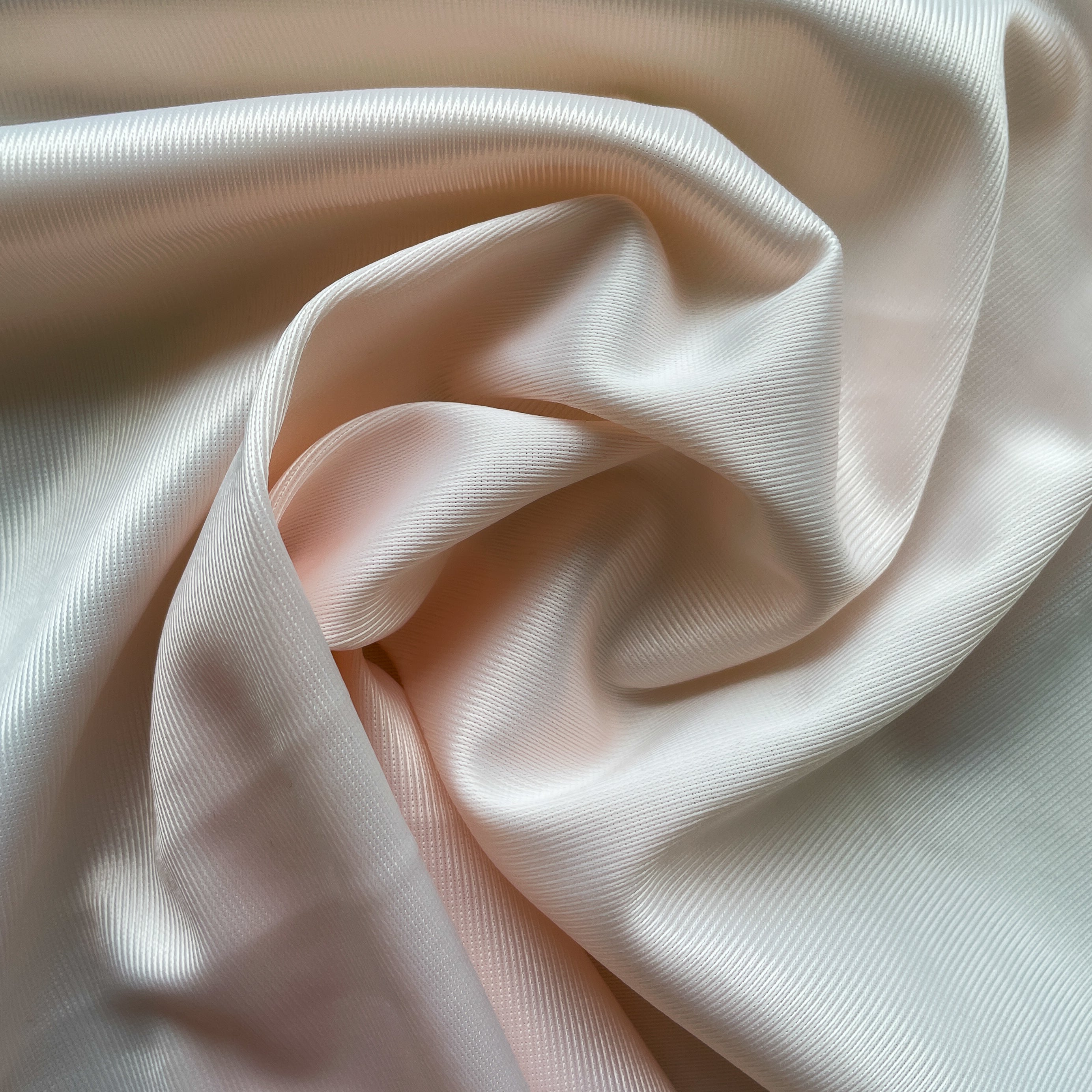 Close up of a soft satin fabric in the color pink from Rubies Custom Bras. We use only the softest bra materials that won't itch or cause allergies. Our fabrics are long lasting and high quality. Book a online fitting appointment to have a custom bra made today. A custom bra is worth the price because it is custom made to fit and made to last years.