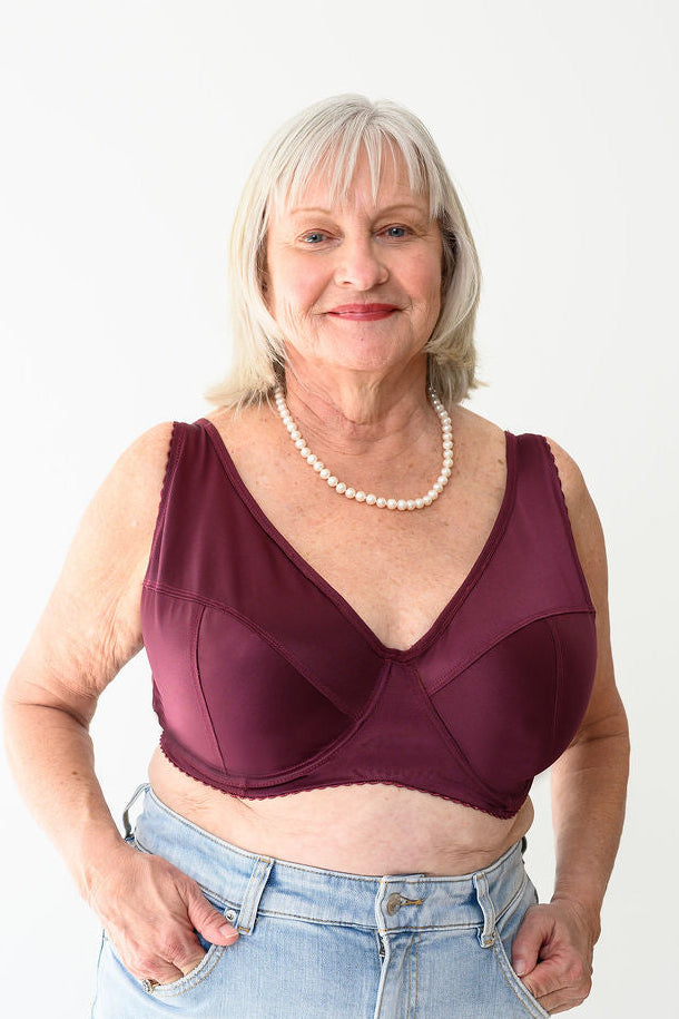 Woman wearing a Rubies Rani Bra in Black Cherry and light blue jeans on a white background