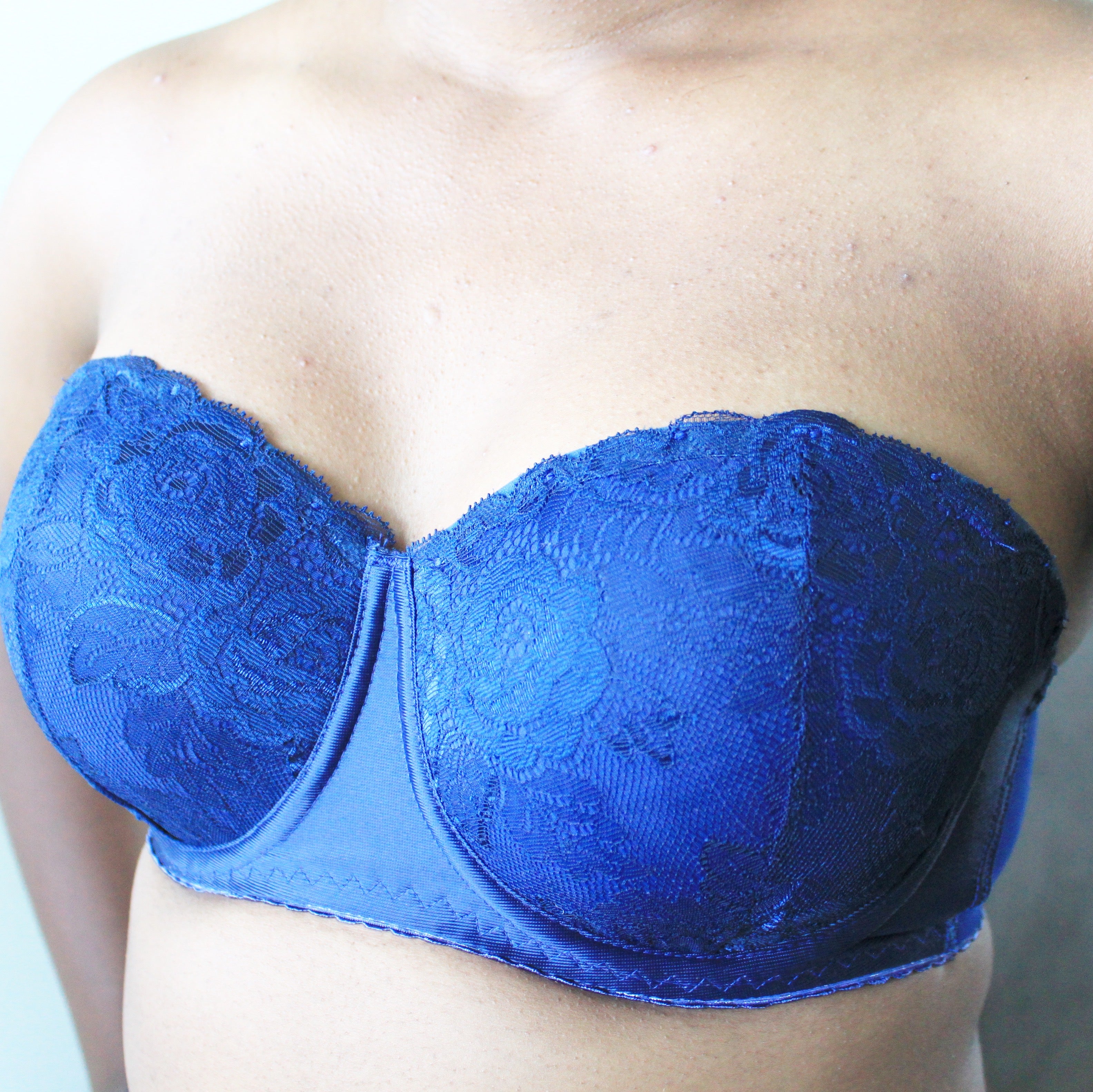 A closeup of a model's chest wearing a strapless solid lace blue bustier from Rubies Custom Bras