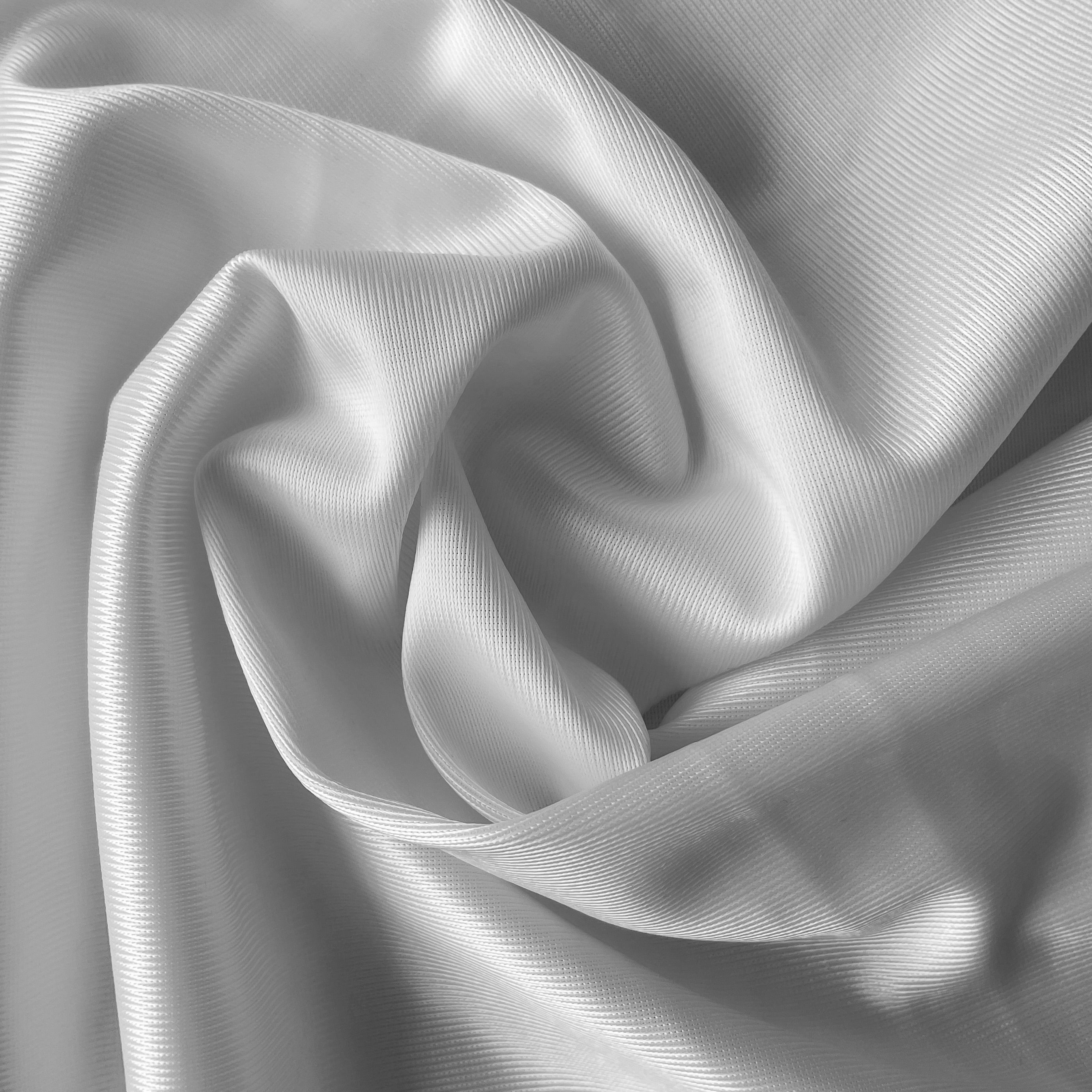 Close up of a soft satin fabric in the color white from Rubies Custom Bras. We use only the softest bra materials that won't itch or cause allergies. Our fabrics are long lasting and high quality. Book a online fitting appointment to have a custom bra made today. A custom bra is worth the price because it is custom made to fit and made to last years.