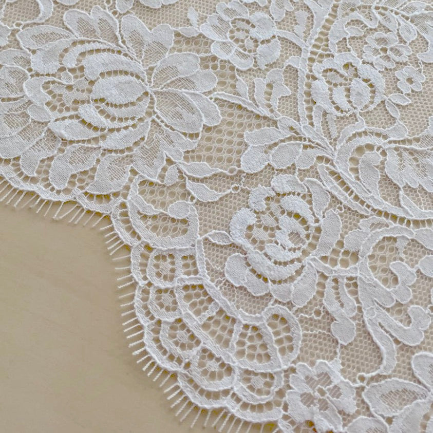 Close up of lace in the color white from Rubies Custom Bras. Our fabrics are long lasting and high quality. Book a online fitting appointment to have a custom bra made today. A custom bra is worth the price because it is custom made to fit and made to last years.