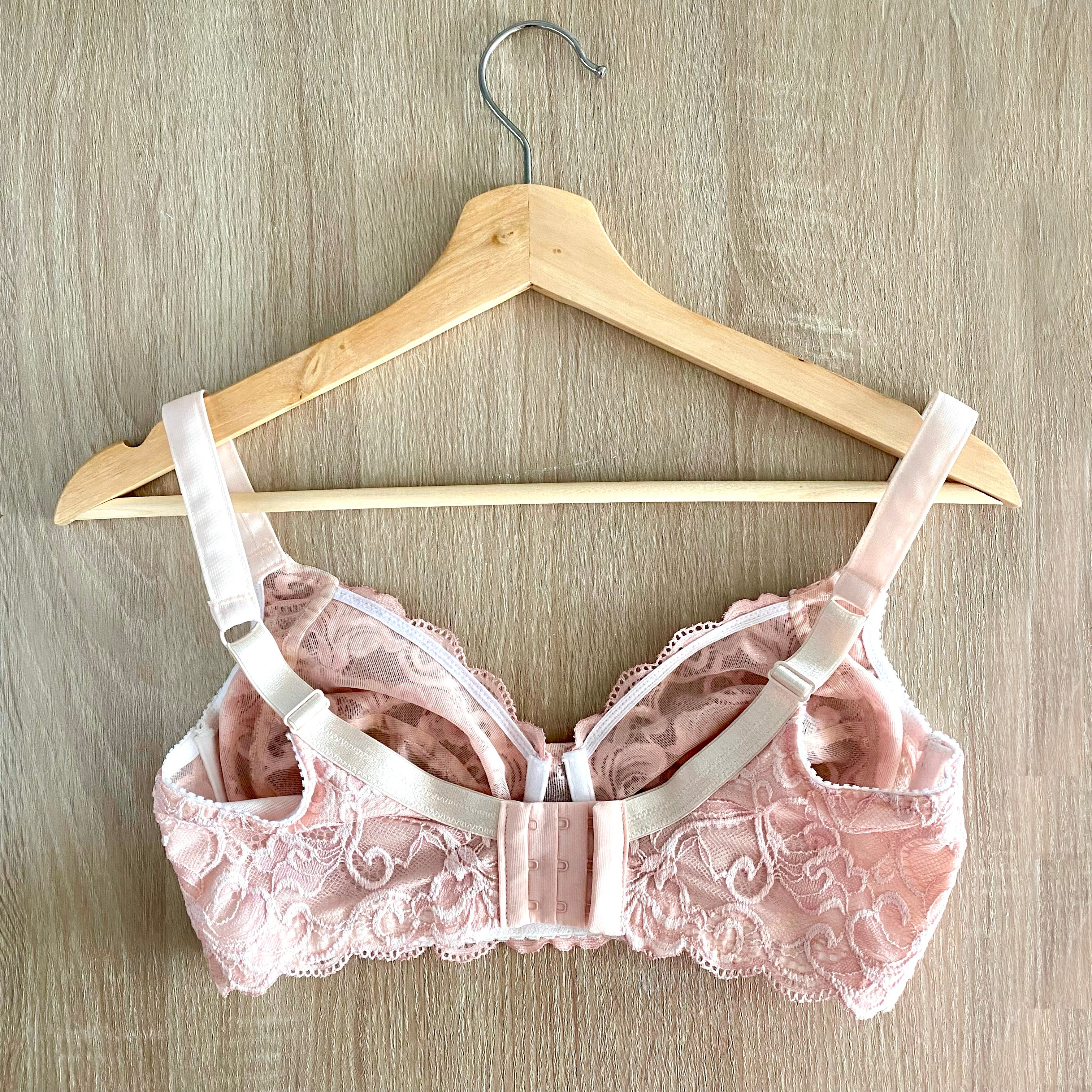The back of a pink wirefree bra from Rubies Custom Bras laying on a wooden surface. 