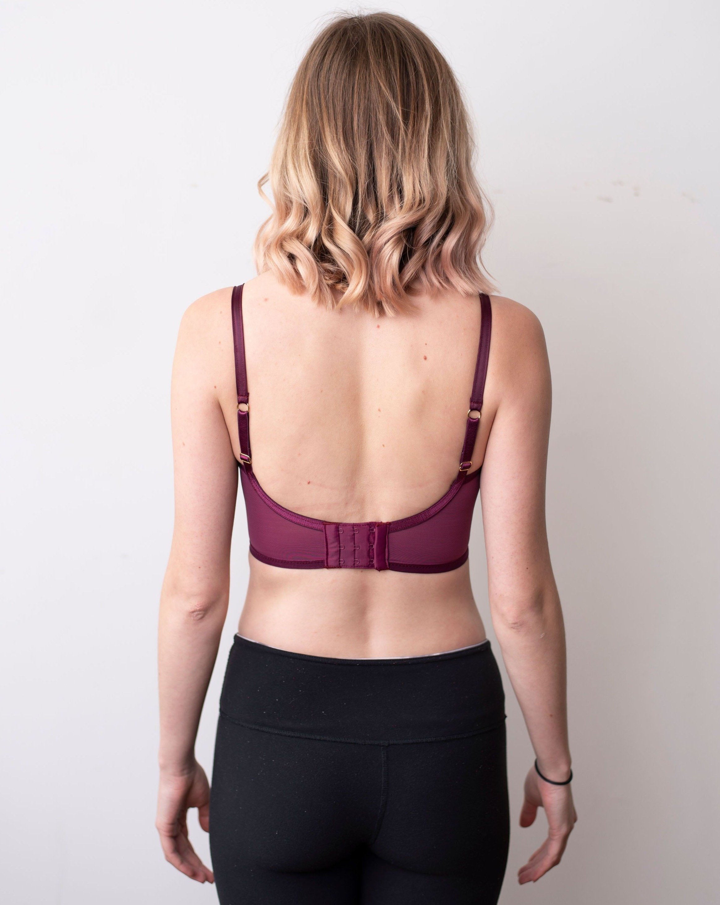 Back shot of model again plain white background. Wearing black cherry minimal solids bra.