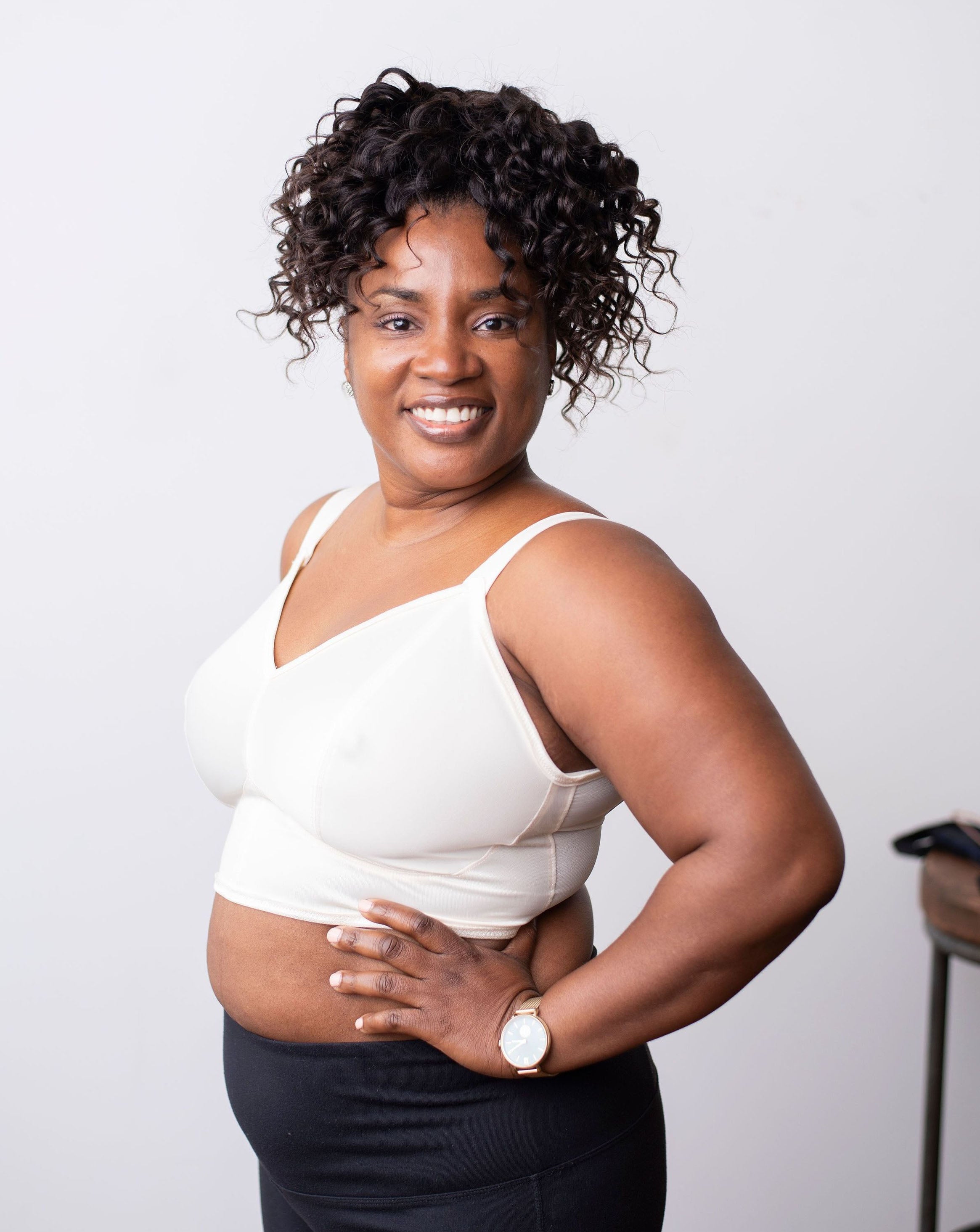 Side shot of a dark skinned model with wavy hair wearing a ivory minimal solids bra.