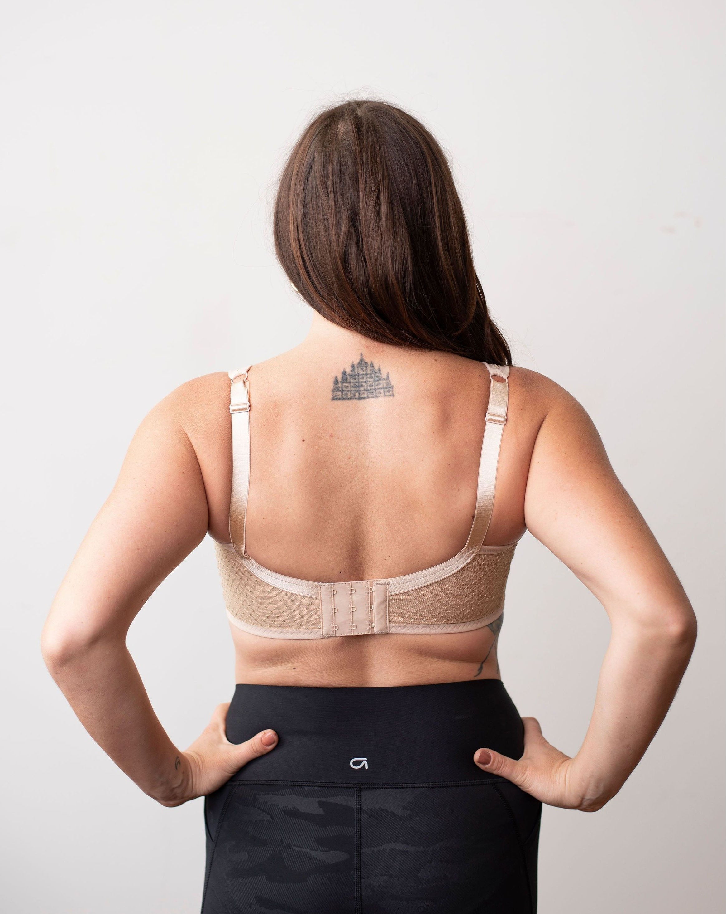 Amanda from Rubies Bras, a female with long brown hair is wearing a beige dotted lace wirefree bra with deep plunge v neck. Back back facing shot on white background.