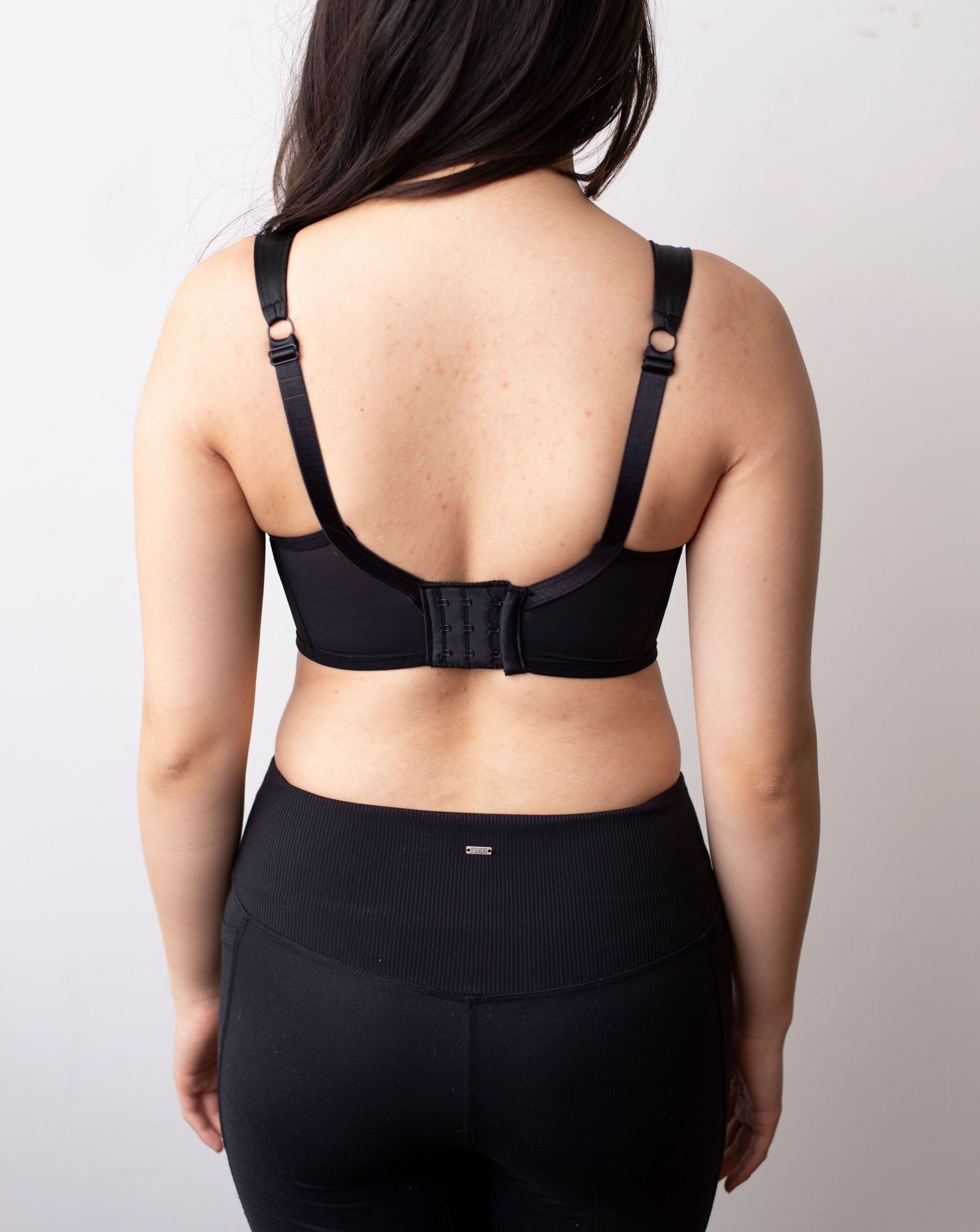 Back shot of black haired model wearing a black minimal solids bra.