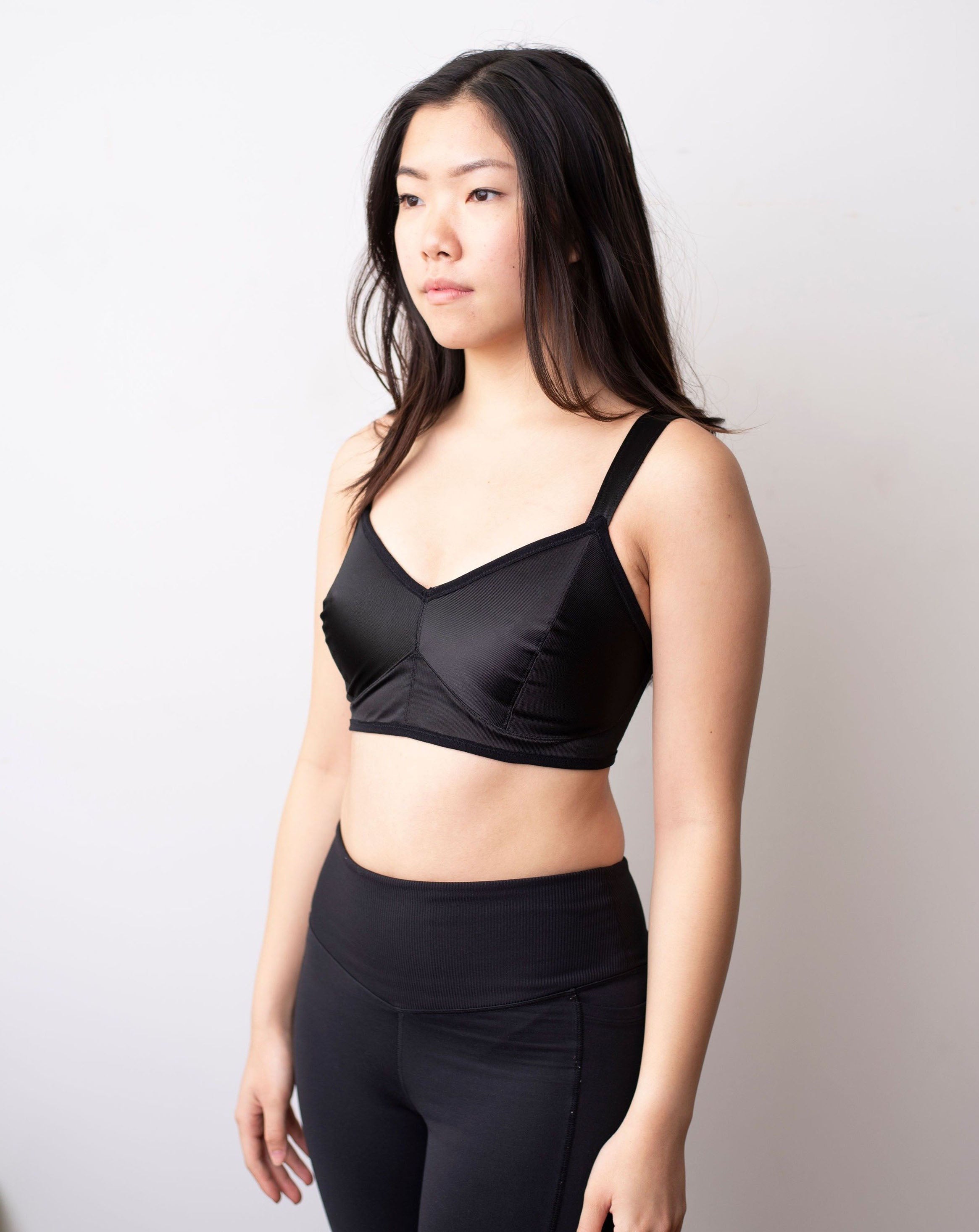 Side shot of black haired model wearing a black minimal solids bra.