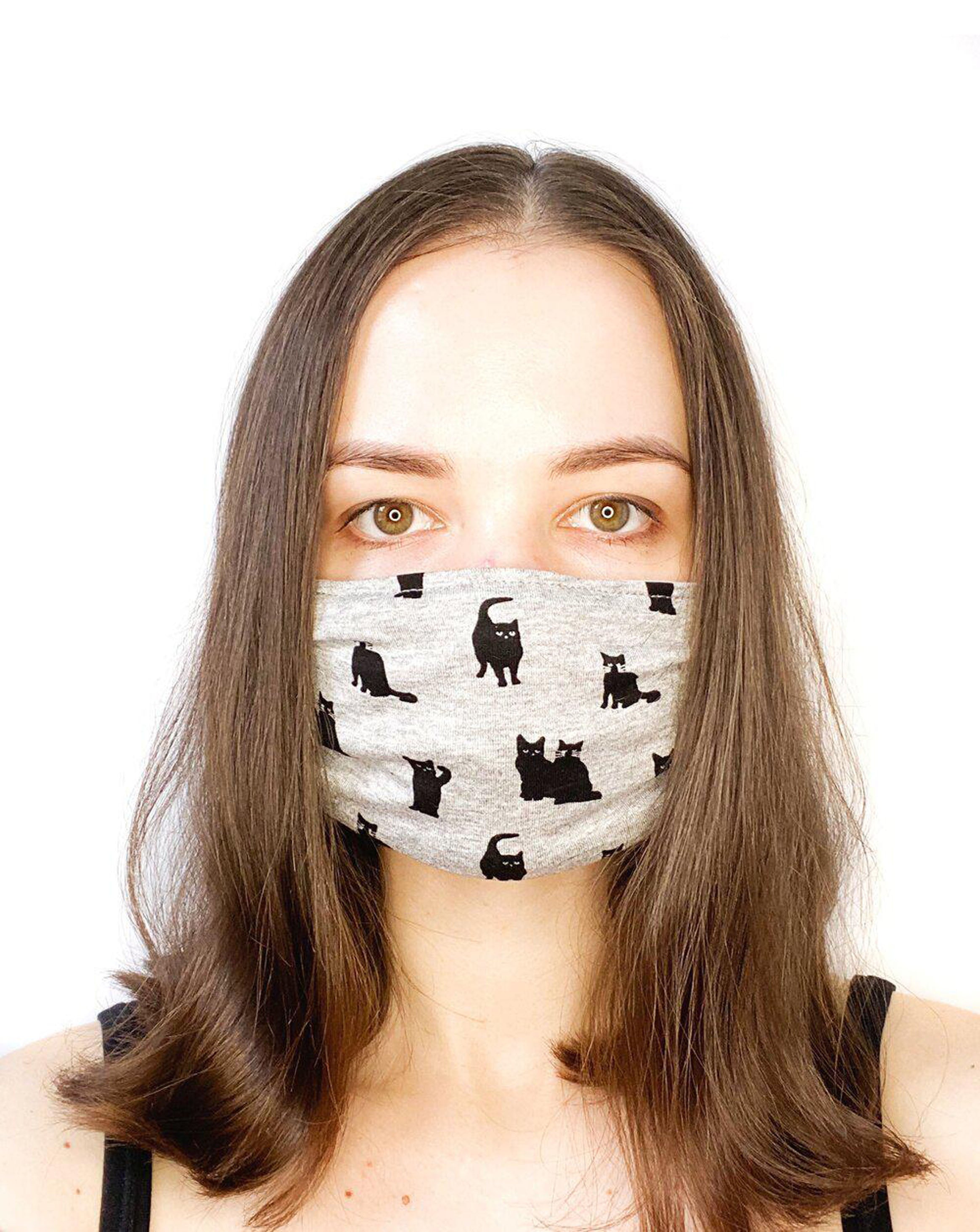 Model with brown hair wearing a black cats on grey, organic cotton facemask.