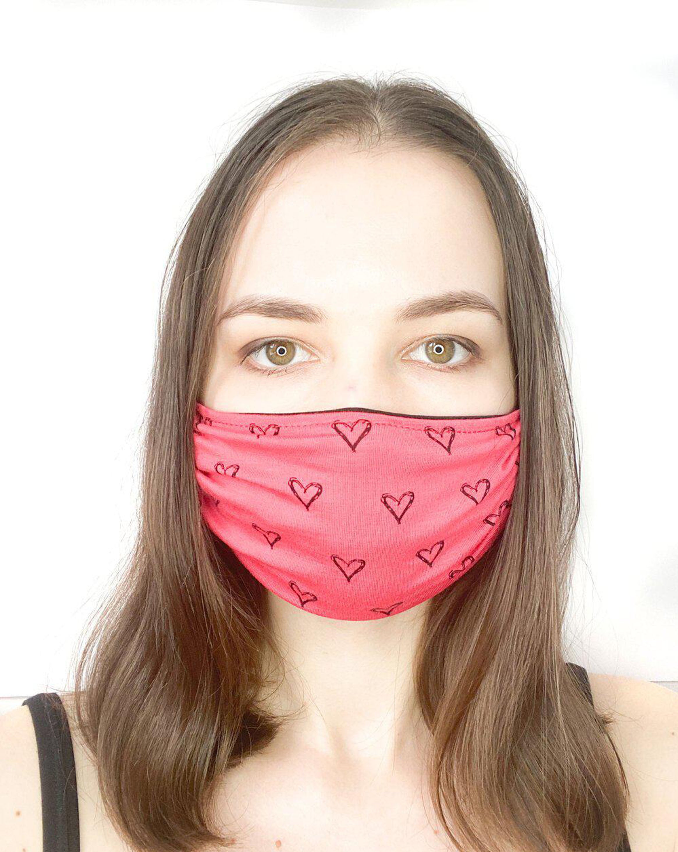 Model with brown hair wearing a black hearts on coral, organic cotton facemask.