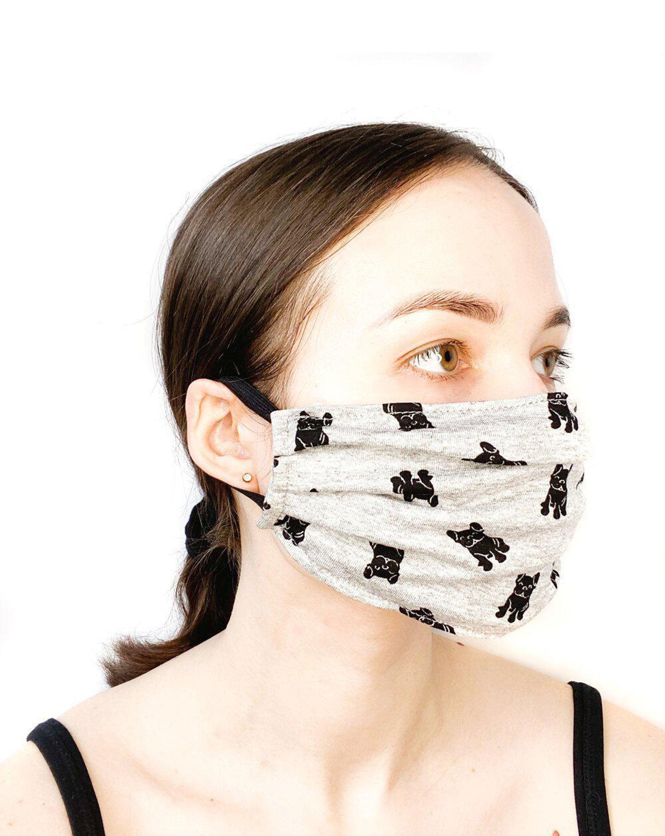 Model with brown hair wearing a black dogs on grey printed mask. Side shot.